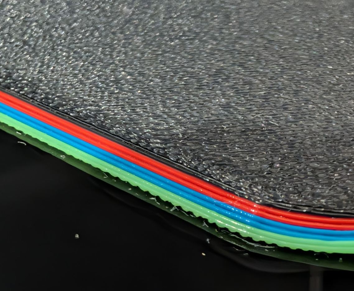 Side view of the mousepad edge showing the layered print structure and chamfer.