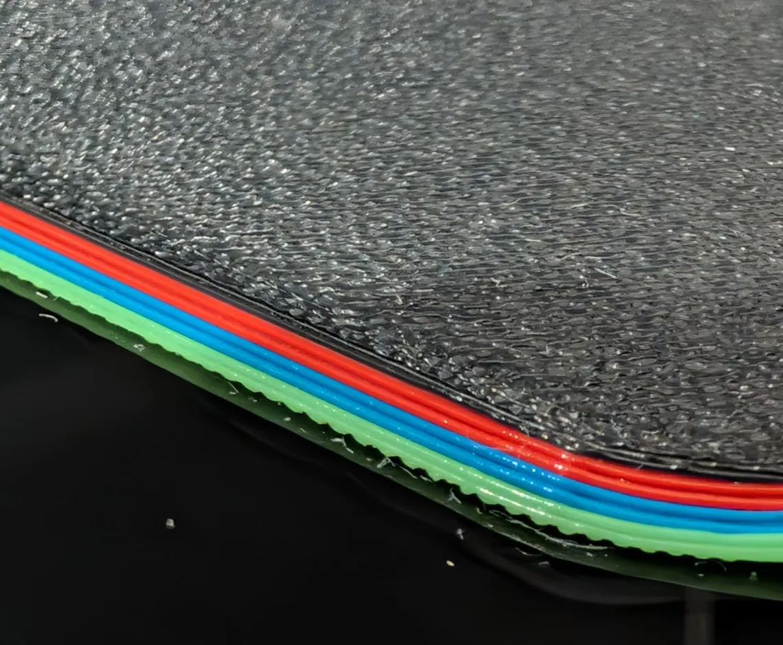 Side view of the mousepad edge showing the layered print structure and chamfer.