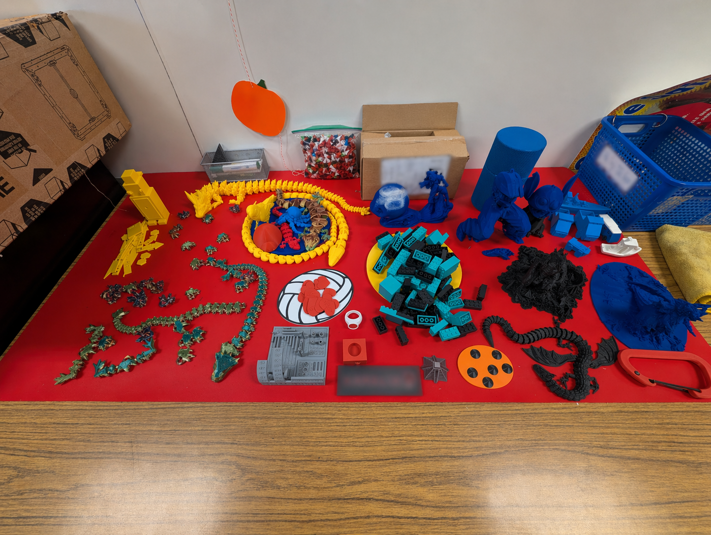 Table full of student prints including articulated dragons, figurines, blocks, and other colorful 3D printed projects from the class.